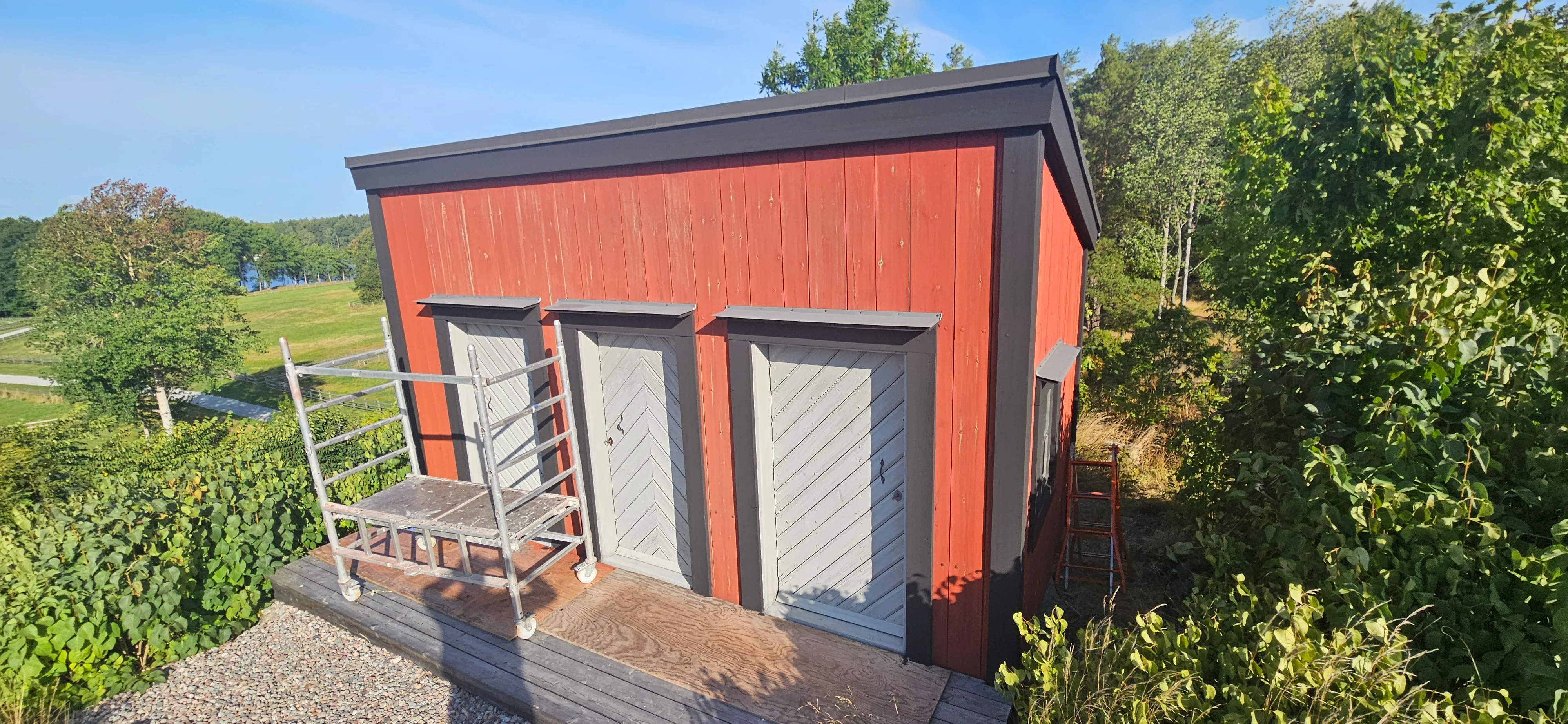 Modernt rött hus bland grön natur