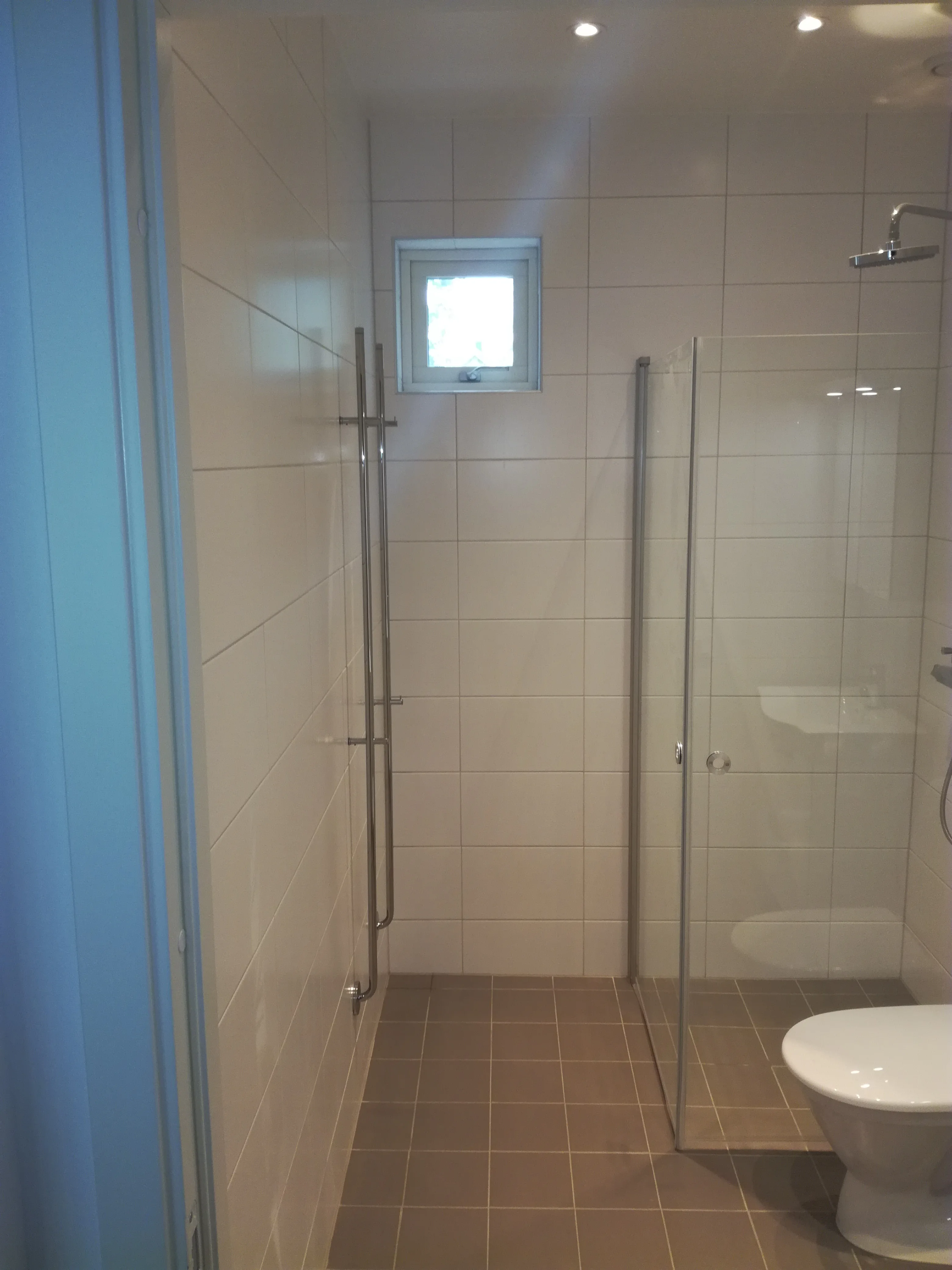 Modernt badrum med glastvätt och vit kakling