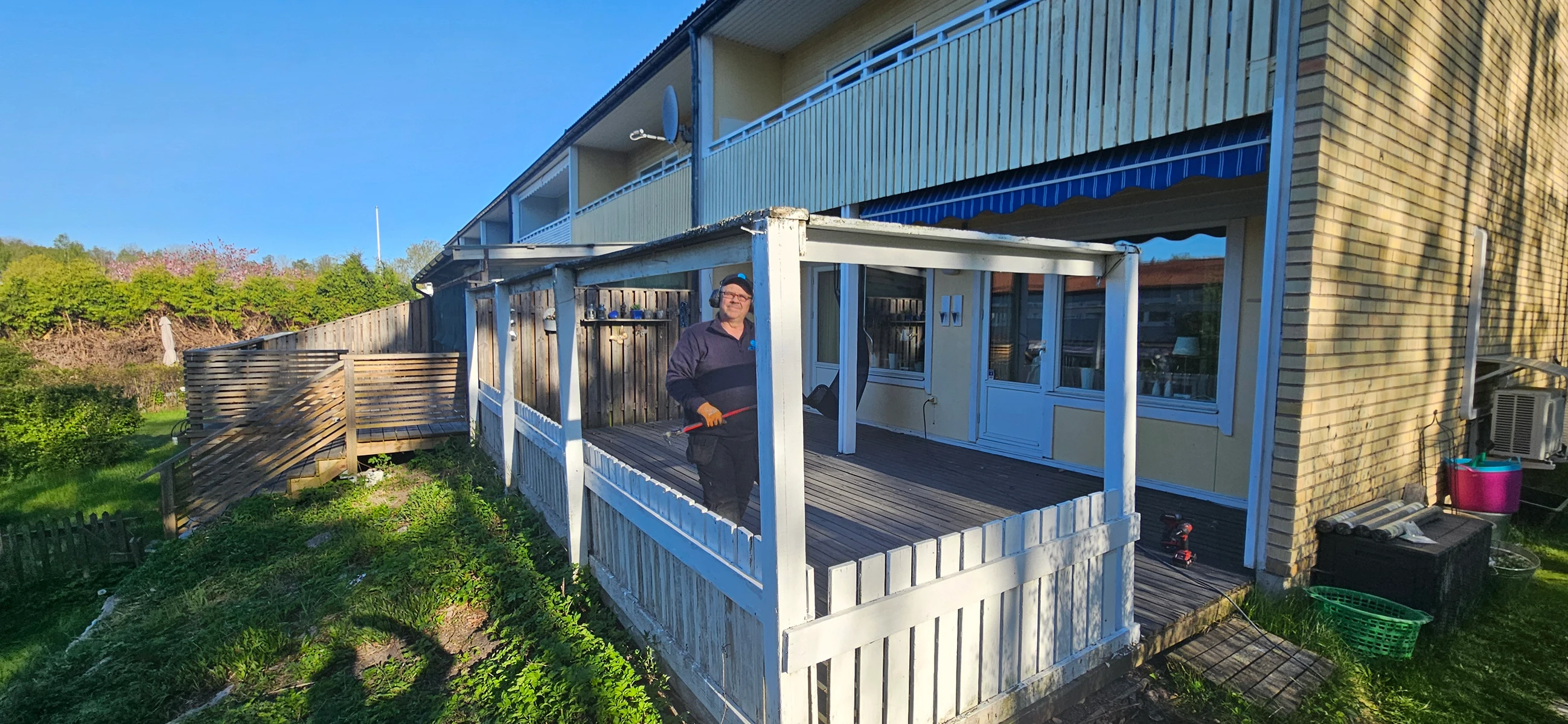 Person står på en altan med träterrass och arbetar med renovering