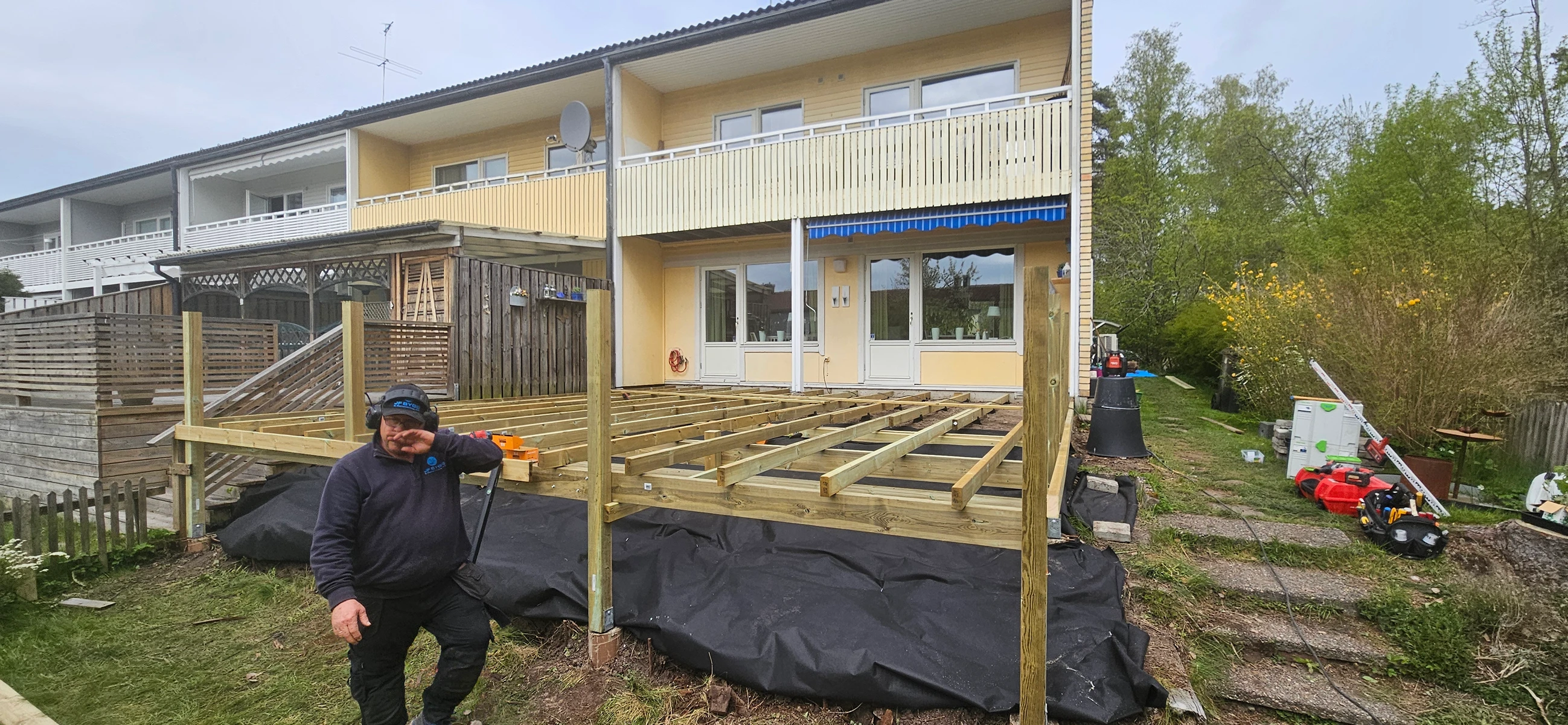 Arbete med altanbygge, en hantverkare står på en träkonstruktion