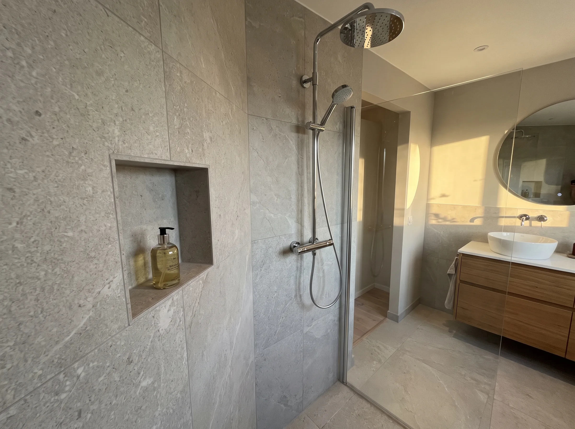 Elegant badrumsrenovering med stengolv och duschplats i modern stil