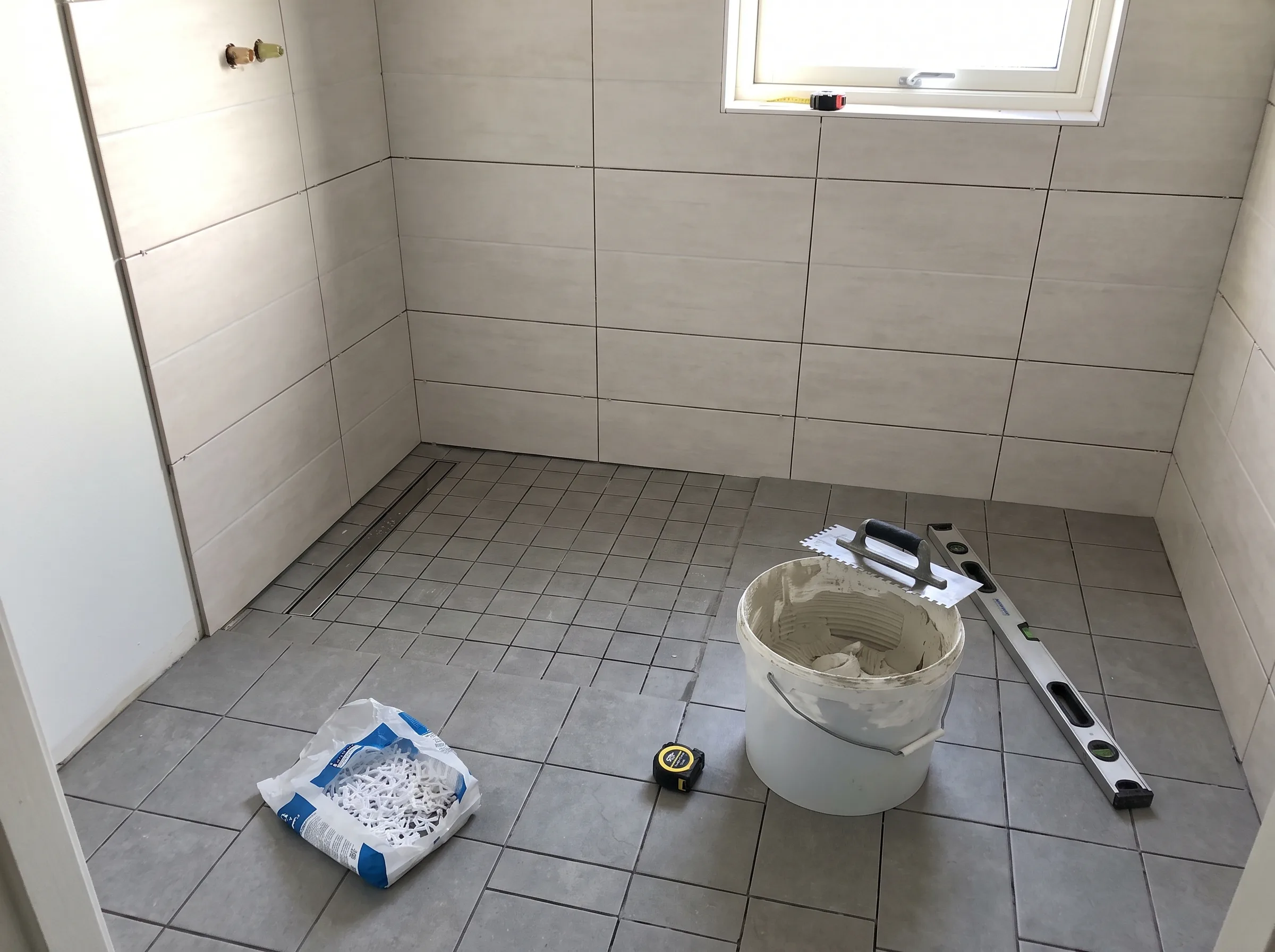 Renovering av badrum med kakel och klinker, verktyg och material synliga i rummet