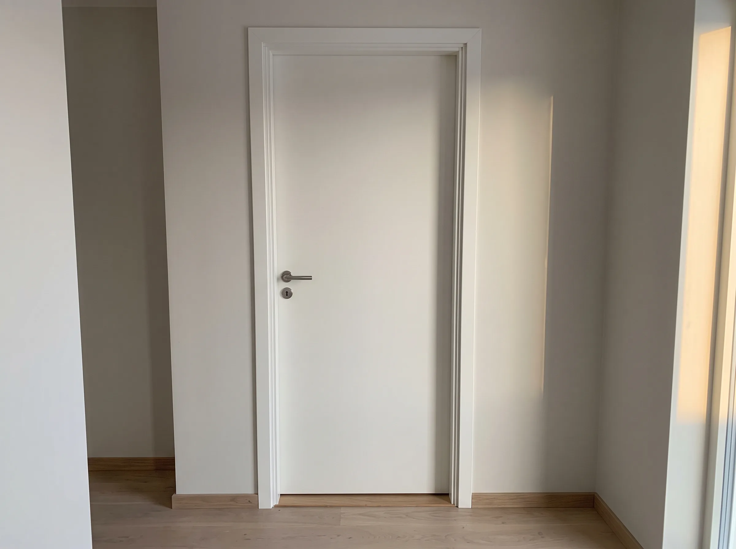 Inredning av en dörr i ett nyrenoverat rum med ljusa väggar och golv