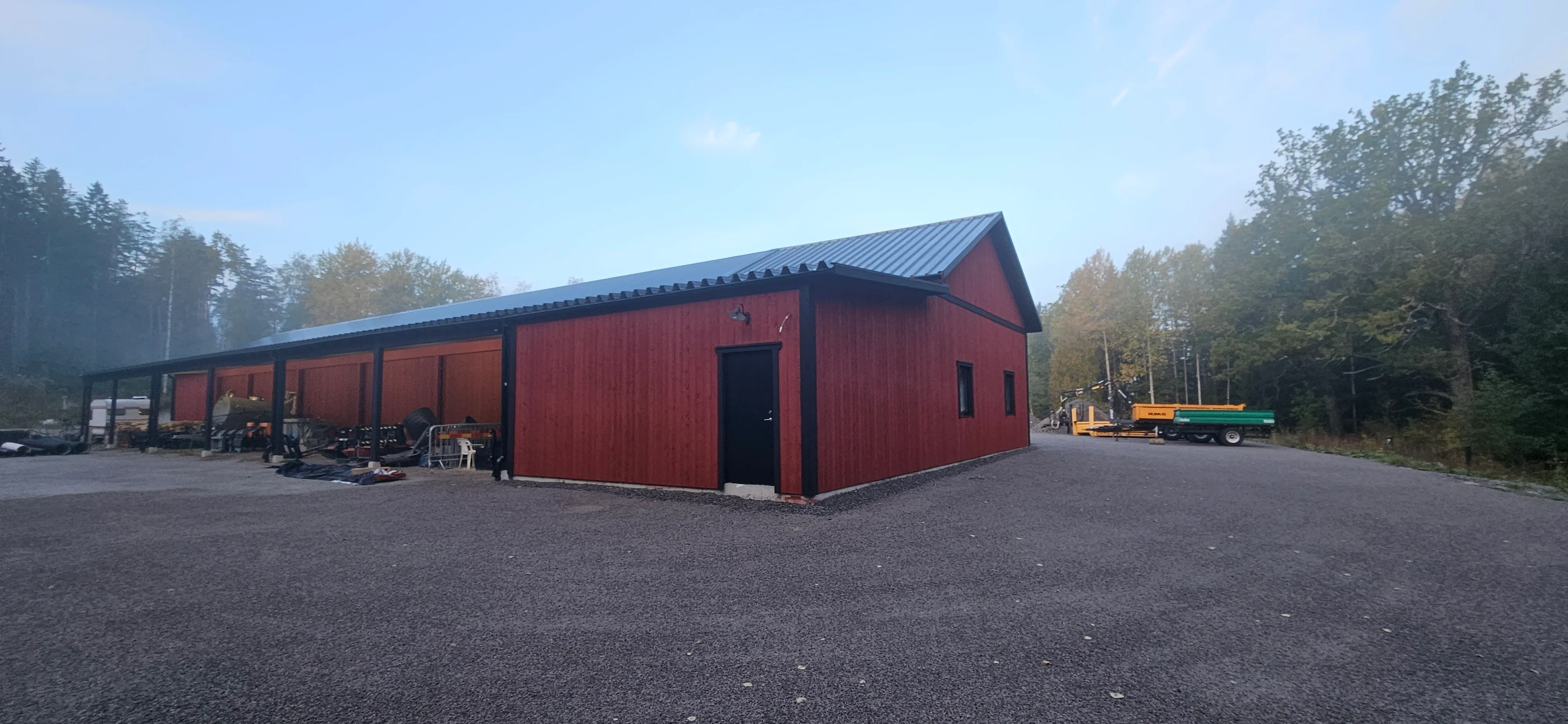 Nybyggnad av en röd träbyggnad med plåttak och parkeringsyta