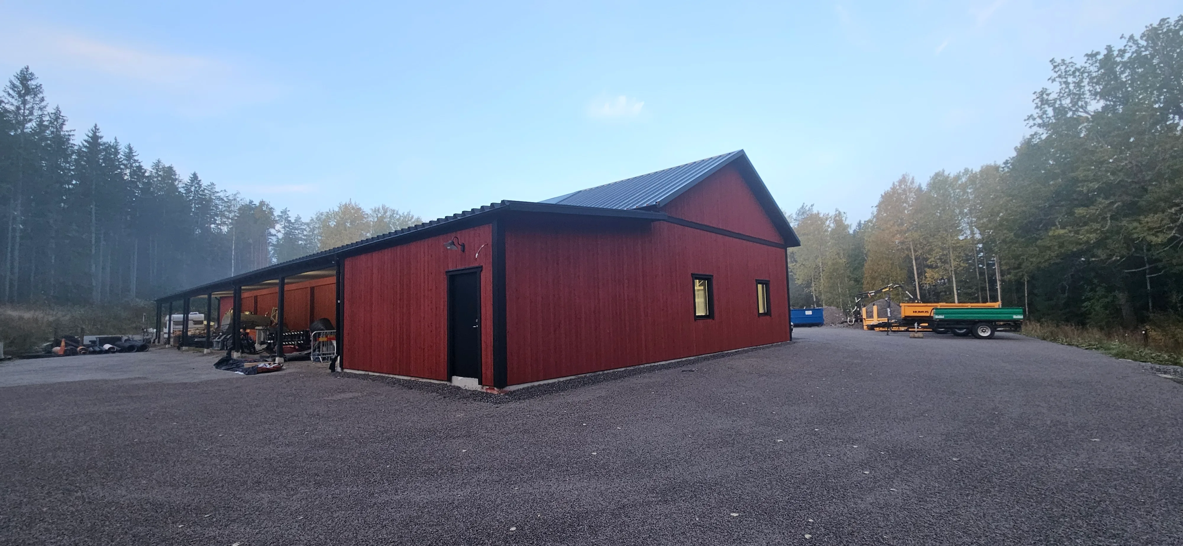 Nybyggnation av en röd byggnad med tak av plåt omgiven av träd