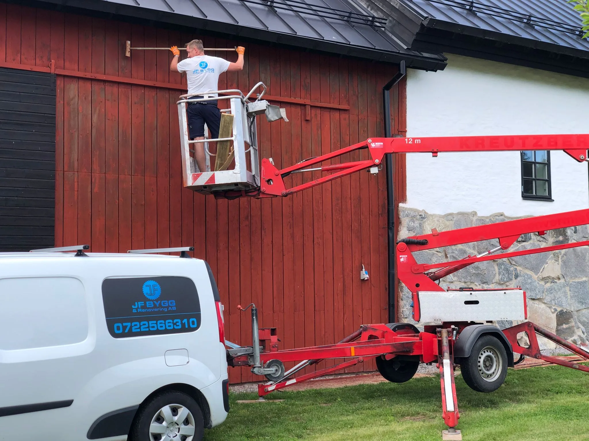 En arbetare som målar en fasad med hjälp av en skylift
