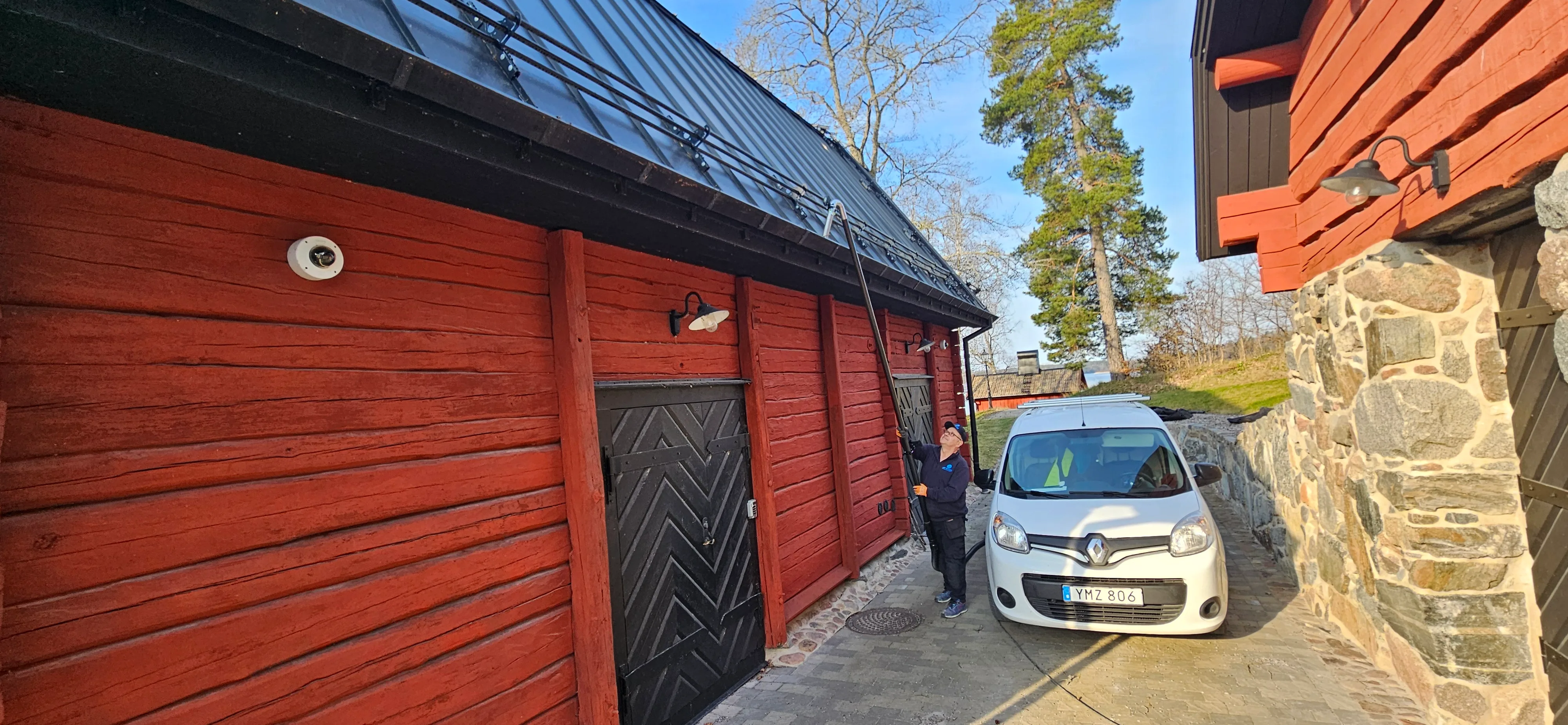 Renovering av en röd träbyggnad med svart tak och en bil parkerad framför