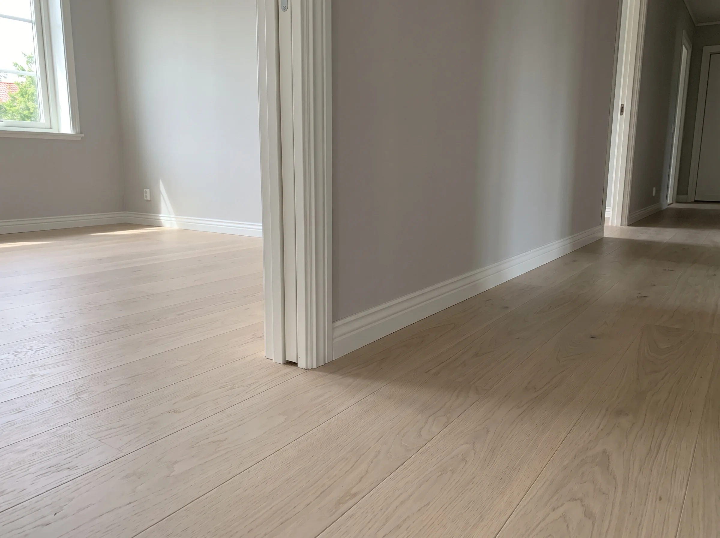 Ljust rum med ny golvläggning och vita väggar, perfekt för lägenhetsrenovering