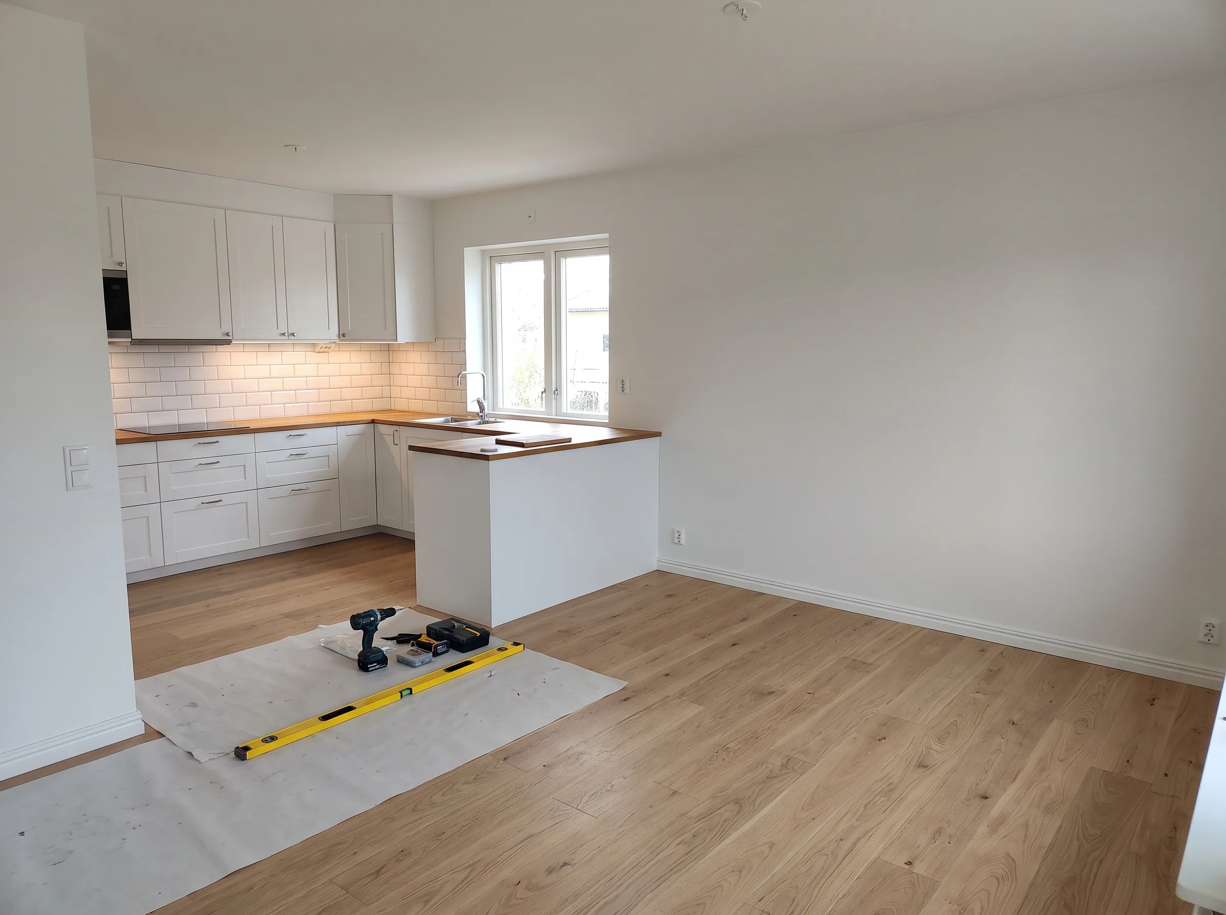 Modernt kök med ny golvläggning och vit inredning, del av lägenhetsrenovering