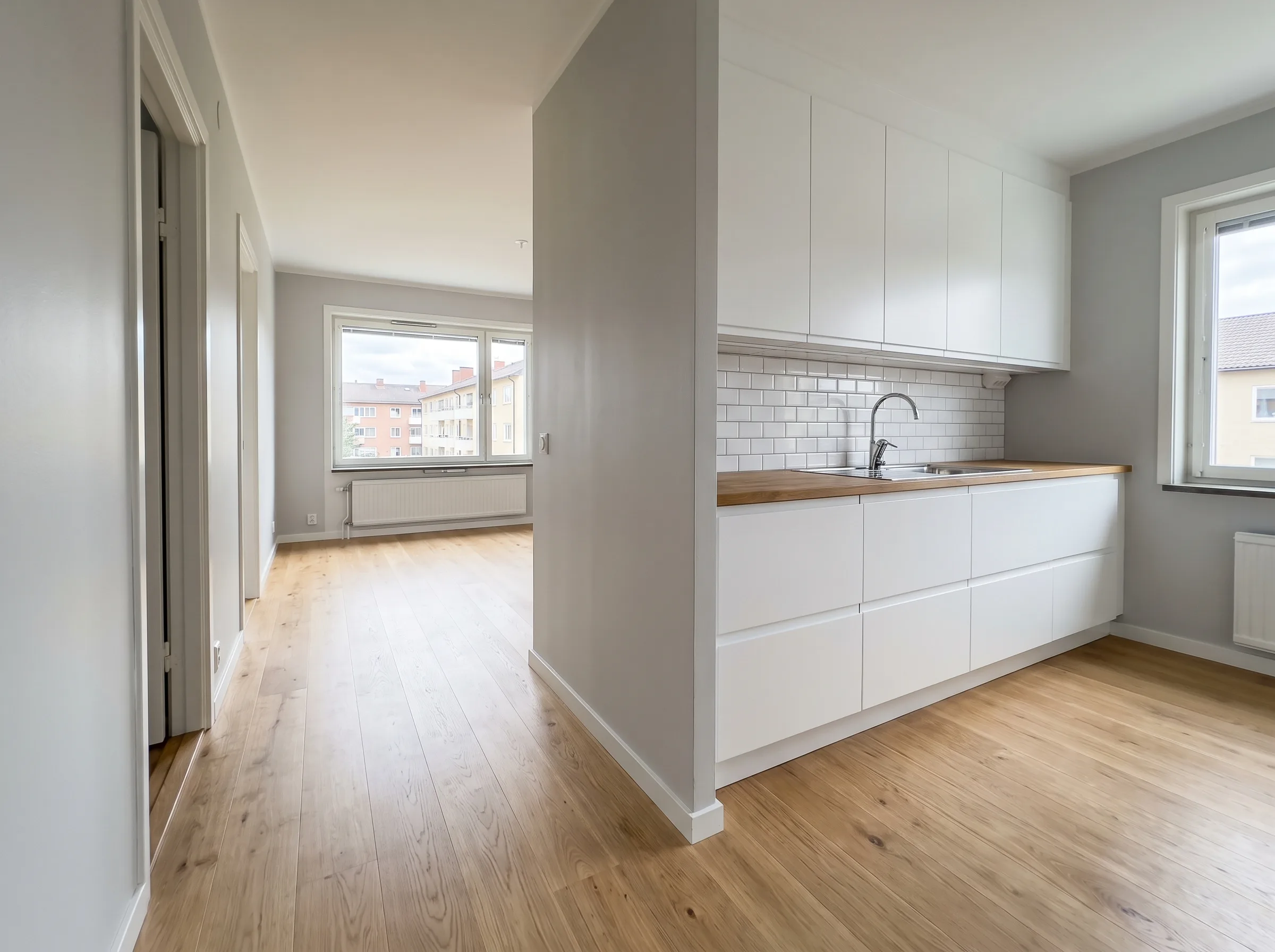 Ljus och modern köksrenovering med vita skåp och träbänkskiva