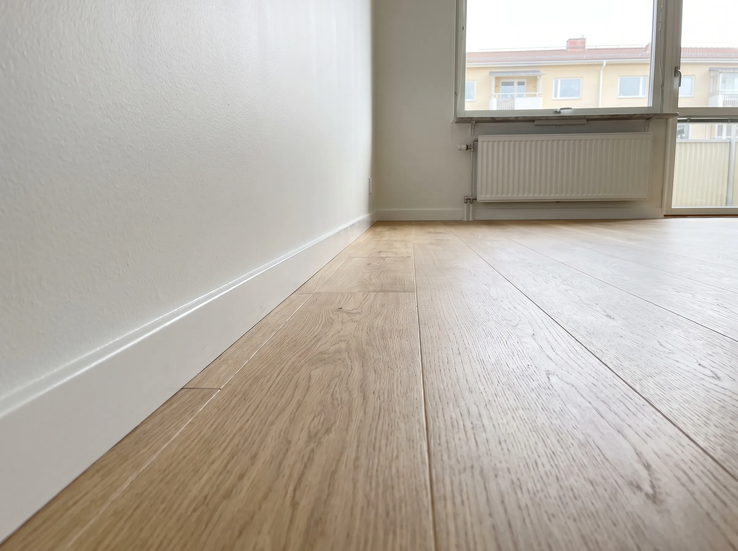 Nyinstallerat trägolv med golvlister i ett ljust rum