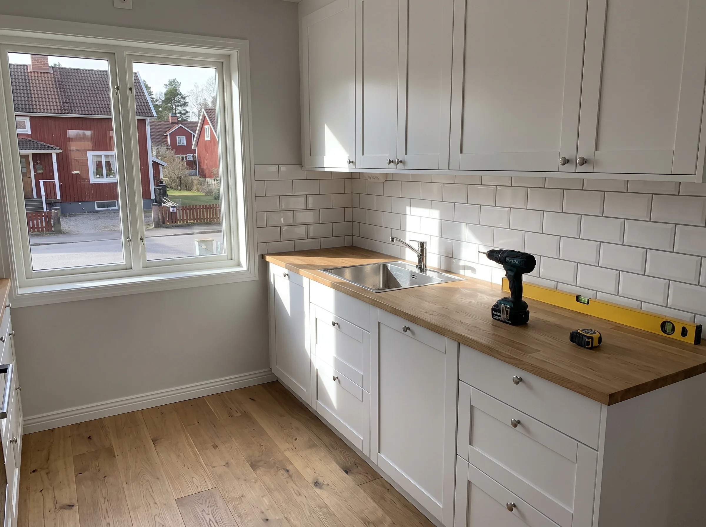 Renoverat kök med vit kakelvägg och träbänk, verktyg på arbetsyta