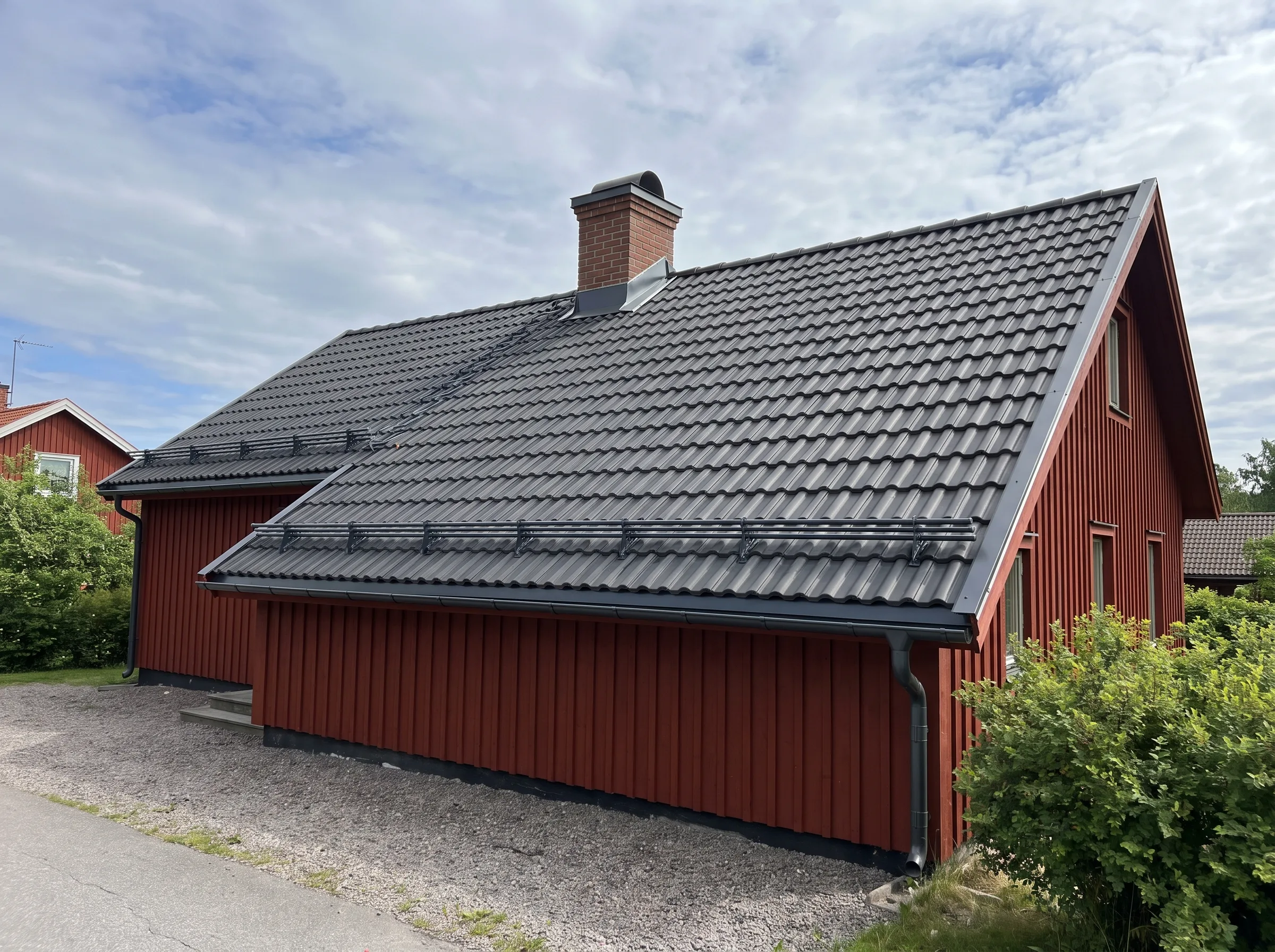 Röd fasad med takrenovering och nya takpannor på en villa