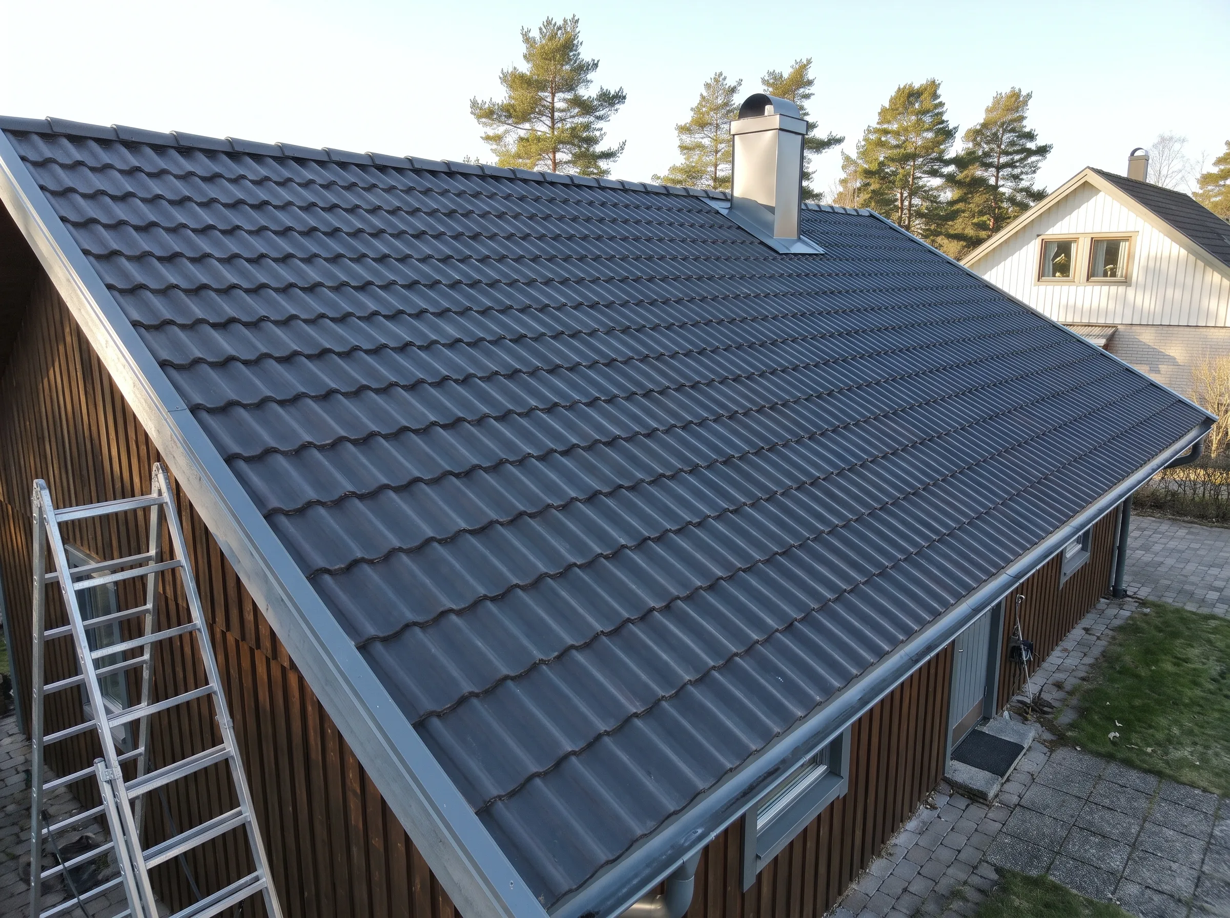 Takläggning med plattor på taket av en villa, med en stege i förgrunden