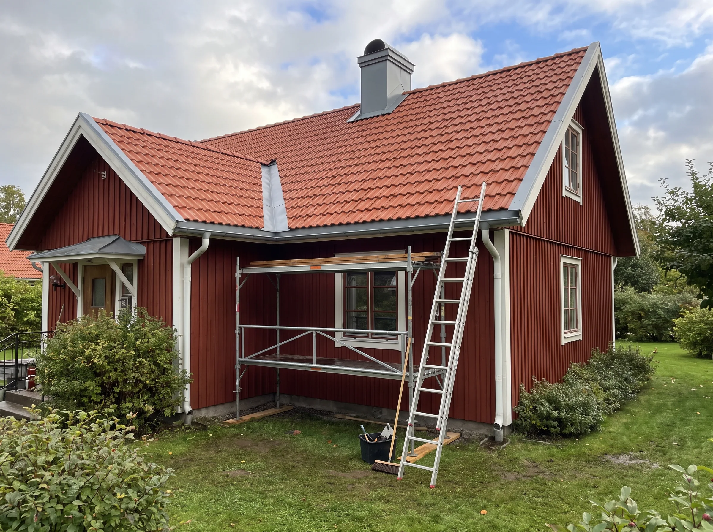 Renovering av fasad med ställning och takarbete på röd stuga