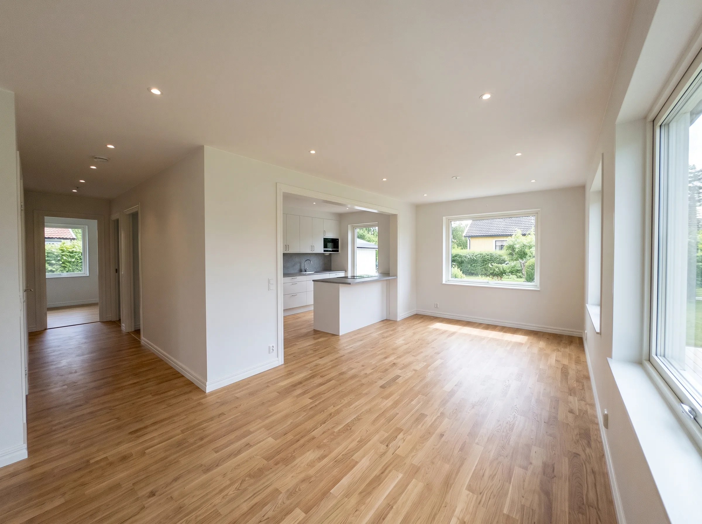 Ljust och rymligt rum med nylagt trägolv och fönster mot trädgård, perfekt för husrenovering